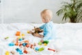 Boy playing with wooden biplane near colorful toy blocks on bed Royalty Free Stock Photo