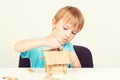 Boy playing with wooden blocks at home. Smart kid builds a little house. Creative leisure for kids