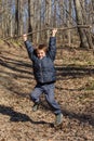 A boy is playing with a wooden stick in the woods Royalty Free Stock Photo