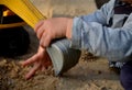 Boy playing with a yellow excavator, his hands and toothed wheels are visible. Hands playing in the sand in the sandbox preschool Royalty Free Stock Photo