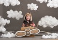 The boy plays in an airplane made of cardboard box and dreams of becoming a pilot, clouds of cotton wool on a gray background