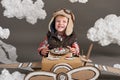 The boy plays in an airplane made of cardboard box and dreams of becoming a pilot, clouds of cotton wool on a gray background Royalty Free Stock Photo