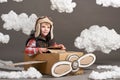 The boy plays in an airplane made of cardboard box and dreams of becoming a pilot, clouds of cotton wool on a gray background Royalty Free Stock Photo