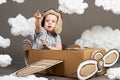 The boy plays in an airplane made of cardboard box and dreams of becoming a pilot, clouds from cotton wool on a gray background, r Royalty Free Stock Photo