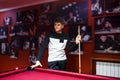 Boy plays billiard or pool in club. Young Kid learns to play snooker. Boy with billiard cue strikes the ball on table.