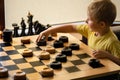 Boy plays checkers and makes a move with his hand. Chess board with checkers. Board game. Hobby. checkers on the playing field for Royalty Free Stock Photo