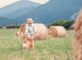 Boy plays with dog on the field with hayroll