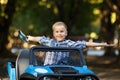 The boy plays, drives a car in the park. A cute little boy Royalty Free Stock Photo