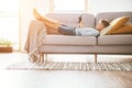 Boy plays with electronic devices - gamepad connected with smartphone lying on the cozy sofa in the home living room Royalty Free Stock Photo