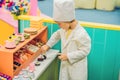 The boy plays the game as if he were a cook or a baker in a children`s kitchen Royalty Free Stock Photo