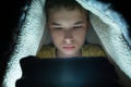 Boy plays games on a smartphone at night under a blanket on the floor Royalty Free Stock Photo