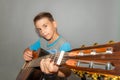 A boy plays the guitar on a gray background in the studio, wide-angle close-up photo Royalty Free Stock Photo