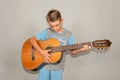 A boy plays the guitar on a gray background in the studio, wide-angle close-up photo Royalty Free Stock Photo