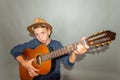 A boy plays the guitar on a gray background in the studio, wide-angle close-up photo Royalty Free Stock Photo