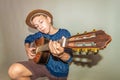 A boy plays the guitar on a gray background in the studio, wide-angle close-up photo Royalty Free Stock Photo