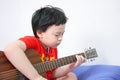 The boy plays the guitar with his left hand, a song by himself, on the sofa, in the bedroom, reading the sheet music Royalty Free Stock Photo