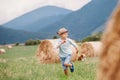 Boy plays with his dog on the mountain fild wit hay roll