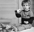 Boy plays with lego on wooden wall background. Nursery game and childhood concept. Toddler with curious face Royalty Free Stock Photo