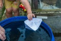 A boy plays with paper boat in the water barrel in the garden Royalty Free Stock Photo