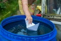 A boy plays with paper boat in the water barrel in the garden Royalty Free Stock Photo