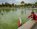 Boy plays with a sailboat at the pond at Luxembourg Gardens