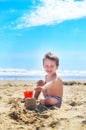 A boy plays with sand and builds sand castles on the seashore Royalty Free Stock Photo