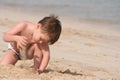 The boy plays sand on seacoast