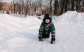 Boy plays in the snow. Crawls along a snowy path among snowdrifts in the winter city park.