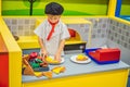 The boy plays in the toy kitchen, cooks a pizza