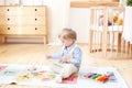 The boy plays with wooden toys at home. Educational wooden toys for the child. Portrait of a boy sitting on the floor in the child Royalty Free Stock Photo