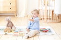 A boy plays with wooden toys and shows the number 2. Educational wooden toys for a child. Portrait of a boy sitting on the floor i Royalty Free Stock Photo