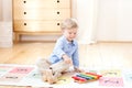 The boy plays xylophone at home. Cute smiling positive boy playing with a toy musical instrument xylophone in the children`s white