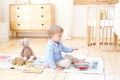 The boy plays xylophone at home. Cute smiling positive boy playing with a toy musical instrument xylophone in the children`s white