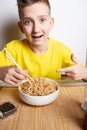 The boy points in surprise at the noodles in the white bowl, a dish of Asian cuisine. Close-up portrait