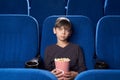 Boy with poker face watching boring film in cinema