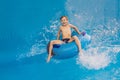 Boy on a pool float on artificial waves in a water park Royalty Free Stock Photo