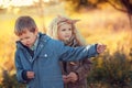 Boy portrays guitarist rock and roll for a cute curly-haired blonde girl in an autumn park