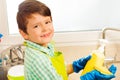 Boy pouring dish soap on sponge in the kitchen