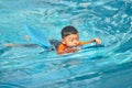 Boy practise swimming with foam pad floater in water