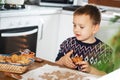 A boy prepares gingerbread cookies in the kitchen. Christmas family traditions. Leisure of the child during the New Royalty Free Stock Photo