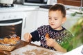 A boy prepares gingerbread cookies in the kitchen. Christmas family traditions. Leisure of the child during the New Royalty Free Stock Photo