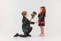 boy presenting roses bouquet to his little girlfriend while standing on knee