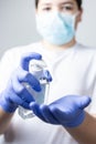 Boy with protective mask and blue gloves washing yours hands with alcohol during coronavirus quarantine