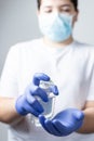 Boy with protective mask and blue gloves washing yours hands with alcohol during coronavirus quarantine