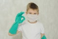 The boy in a protective medical mask and gloves shows arms with a stop sign of the spread of the virus and disease. Quarantine