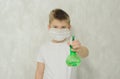 The boy in a protective medical mask sprays a disinfectant or antibacterial spray to prevent the spread of viruses and germs.