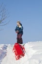 Boy pulling red plastic sledge to a snowy hill Royalty Free Stock Photo