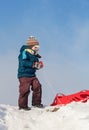 Boy pulling red plastic sledge to a snowy hill Royalty Free Stock Photo