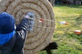 boy pulls arrows from straw target archery archer shooting wooden arrows wings feathers white black jacket cap spring winter