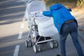 A boy pushes a white stroller with his sister in autumn. Family attitude. Taking care of the brother for the younger sister and Royalty Free Stock Photo